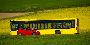 Ein Bus und ein PKW begegnen sich auf einer Landstraße.