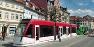 Eine rot-weiße Straßenbahnvor Altbauten