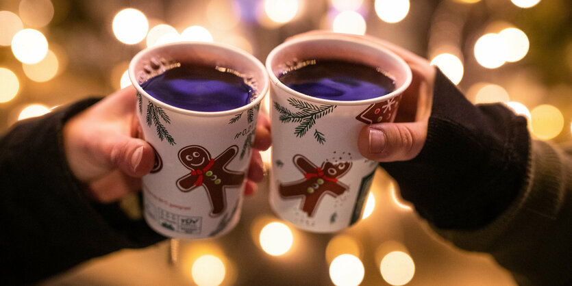 Zwei Menschen halten Becher mit Glühwein