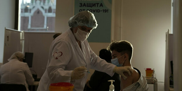 Eine Krankenschwester mit einer Spritze in der Hand und ein Junge