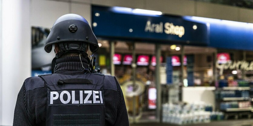 Ein Polizist in Schutzausrüstung vor einer Tankstelle