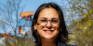 Eine Frau mit schwarzen Haaren und Brille, von der Sonne beschienen