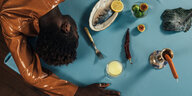 Der Musiker Wayne Snow liegt übergebäugt auf einem Tisch, der merkwürdig gedeckt ist: ein Würstchen steckt in einem Kerzenständer, ein Fisch liegt ungebraten auf einem Teller
