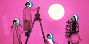 Die vier Musiker:innen von Vanishing Twin vor einer rosa Wand