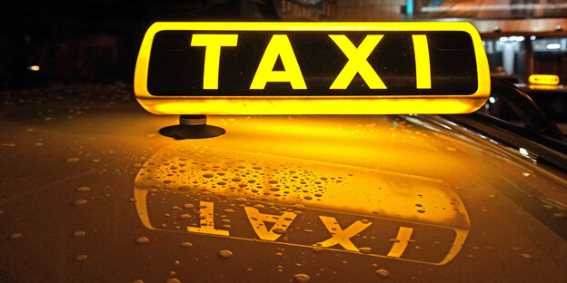 Ein beleuchtetes Taxischild auf einem Autodach.