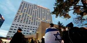 Menschen mit Israel-Fahne vor einem Hotel