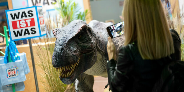 An einem Stand auf der Buchmesse ist ein Dinosauerier zu sehen.
