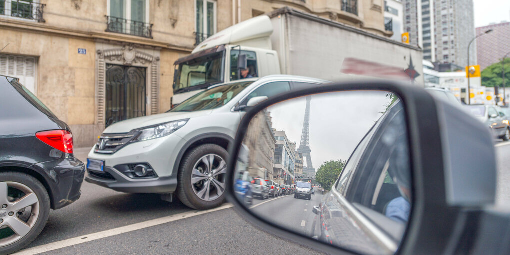 Ein eStraße mit Autos, im Rückspiegel der Eiffelturm.