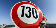 Ein Straßenwärter hält an der Autobahn A81 am Hegaublick ein Schild mit der Aufschrift «130» in den Händen.