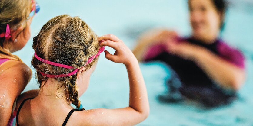 Zwei Mädchen und ihre Schwimmlehrerin in einem Schwimmbad.