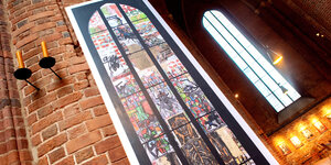 Eine Abbild des von Markus Lüpertz geschaffenen Reformationsfensters lehnt an einer Säule in der Marktkirche