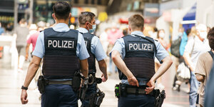 Drei Bundespolizisten im Einsatz; sie laufen offenbar durch einen Bahnhof