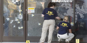 zwei Frauen mit FBI-Shirts vor zersplitterter Glasscheibe