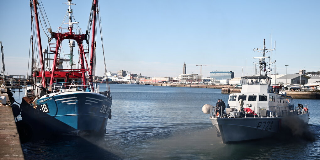 Ein Fischkutter und ein Polizeiboot in einem Hafen.