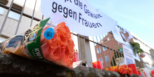 Blumen liegen vor einem Transparent mit der Aufschrift "Stoppt die Gewalt gegen Frauen"
