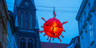 Lampion in Corona-Virus-Form leuchtet vor Schreiner Kirchturm