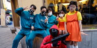 Fünf junge Leute posieren in Kostümen von Squid Game