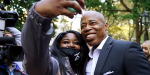 Der Schwarze Eric Adams lächelt für ein Selfie mit einer Wählerin