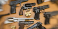 Pistolen und Revolver und Munition liegen auf einem Tisch in der gesicherten Asservatenkammer der Waffenbehörde des Landkreises Osnabrück.