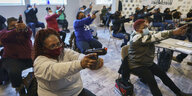 Frauen sitzen auf Stühlen und zielen mit Waffen im Schießtraining