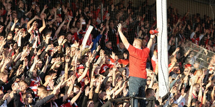 Vorsinger der Fans auf dem Podest dirigiert Cottbusser Anhang auf der Tribüne