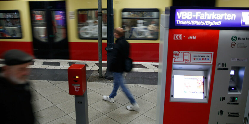 Menschen stehen auf dem Bahnsteig, dahiner eine S-Bahn