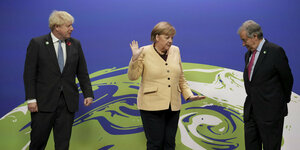 Merkel steht zwischen Johnson und Guterres im Hintergrund eine Weltkugel