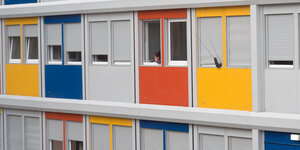 in Kind blickt in Berlin aus einem Fenster der Flüchtlingsunterkunft Alfred-Randt-Straße