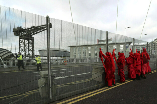Menschen in roten Gewändern stehen vor dem Sicherheitszaun