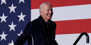 Biden vor einer amerikanischen Flagge lachend