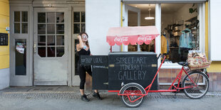 Eine Frau mit einem großen Lastenfahrrad vor einem Haus