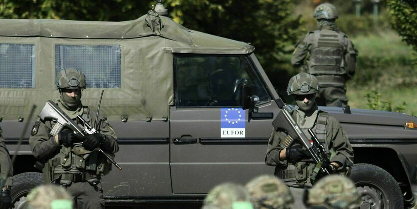 Zwei Soldaten stehen bewaffnet vor einem Jeep