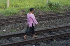 Eine Frau läuft in Indonesien auf den Gleisen entlang