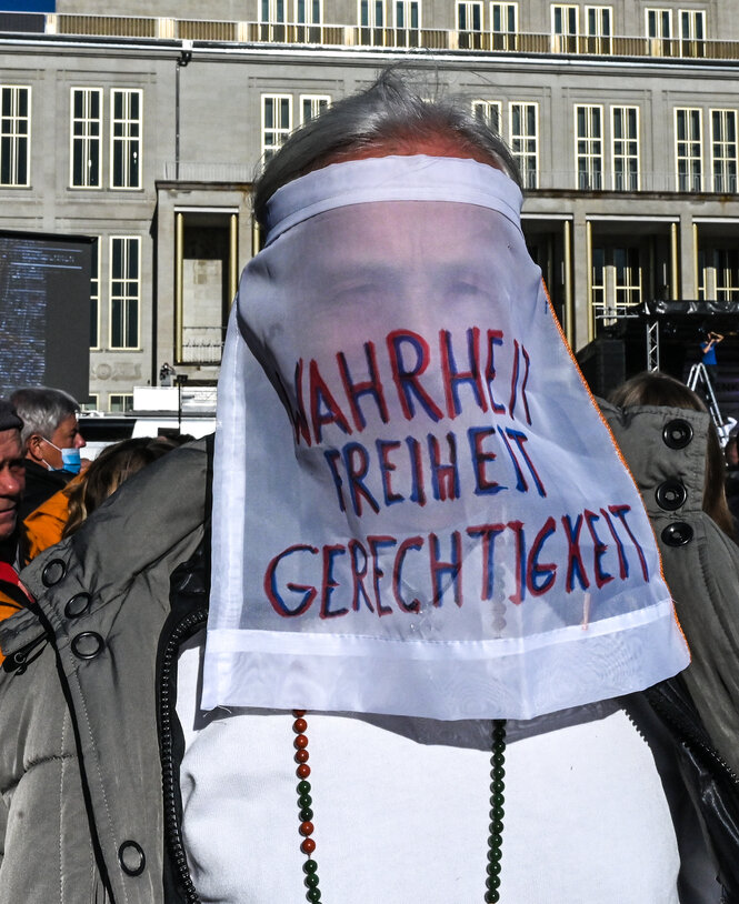 Ein Demonstrant trägt ein Schild mit den Worten Wahrheit Freiheit Gerechtigkeit vor dem Gesicht