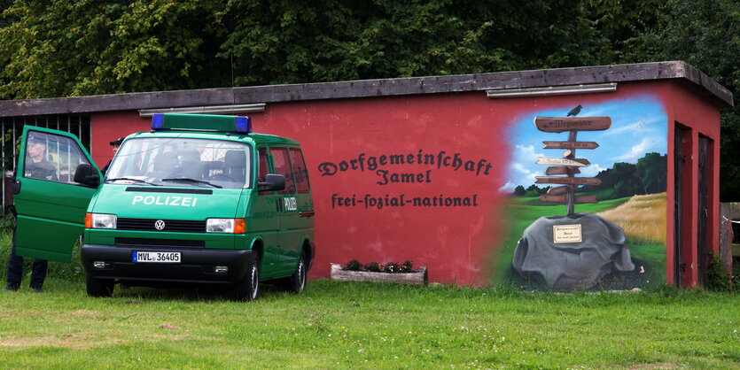 Ein Polizeiauto steht neben einem Grafitti „Frei, sozial, national“