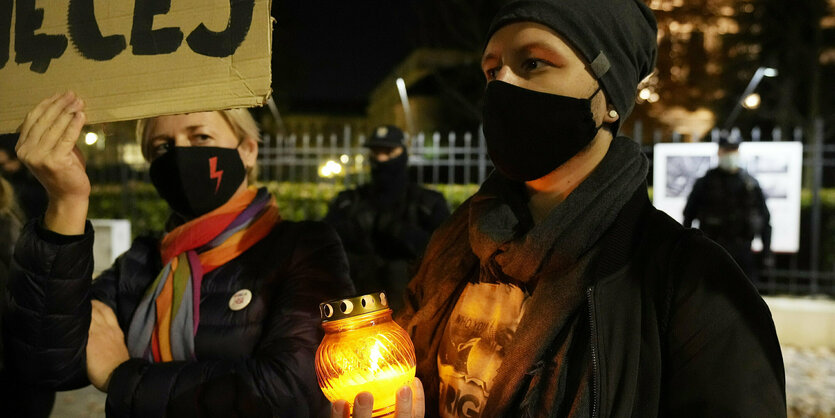 Frauen mit Kerze und Schild auf einer Demonstration.