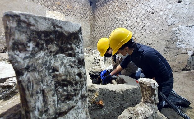Archäologen mit gelven Helmen untersuchen ein Steinbecken