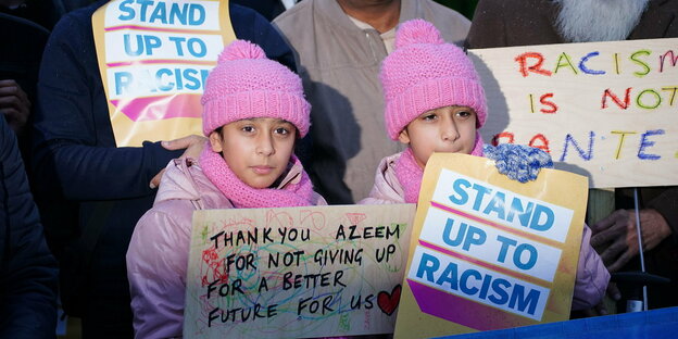 Zwei Mädchen mit Migrationshintergrund halten Unterstützungsplakate für Azeem Rafiq