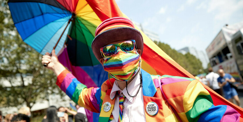 Mann bei strahlendem Sonnenschein mit Regenbogenmaske