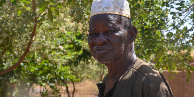 Yacouba Sawadogo, ein älterer Mann mit weißer Kappe und braunem Hemd, blickt in die Kamera