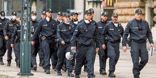 Polizisten in grünen Overalls marschieren in einer Reihe