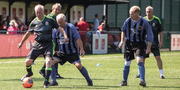 Alte Männer in Trikots spielen Walking Football.