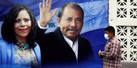 Wahlplakat mit Daniel Ortega und Passant davor.