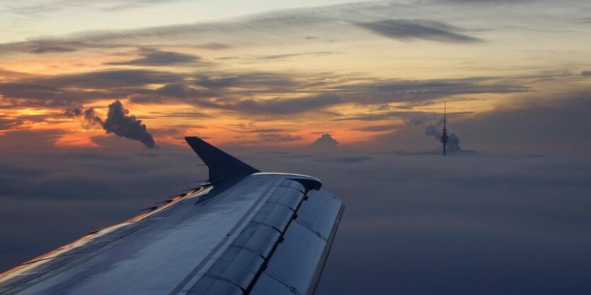 Flugzeug über Wolken, im Hintergrund der Fernsehturm