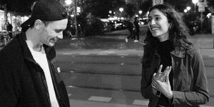 Ein Schwarz-Weiß-Fotografie von Rapper Jan Kawelke und Künstlerin Atusa Jafari. Sie schauen sich an und Jafari lacht