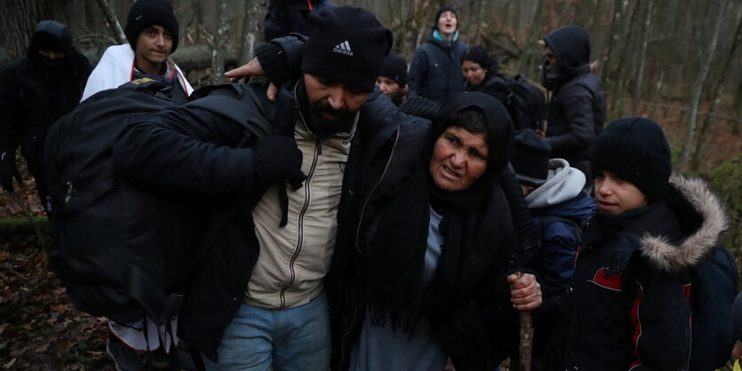 Geflüchtete im Wlad an der polnischen Grenze zu belarus. Eineältere Frau wird von einem Mann aufrecht gehalten.