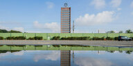 das VW-Hochhaus in Wolfsburg spiegelt sich in einer Pfütze auf dem Mitarbeiterparkplatz