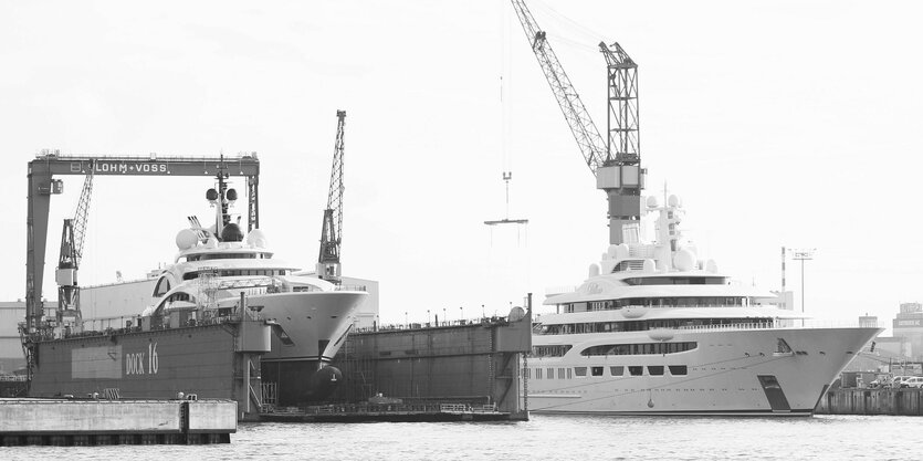 Superyachten in einer Werft mit Kränen.