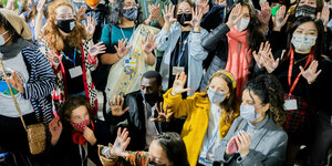 eilnehmer einer Protestaktion von Fridays for Future halten bei der UN-Klimakonferenz COP26 in Glasgow mit Augen bemalte Hände in die Höhe.
