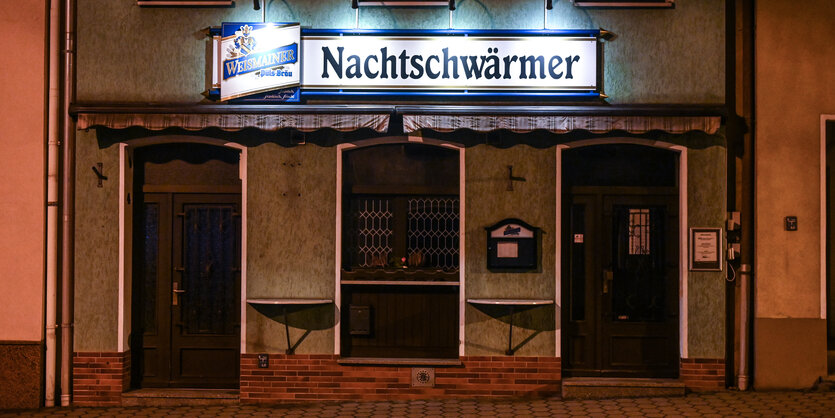 Eine Kneipe namens Nachtschwärmer von außen im Dunkeln angeleuchtet